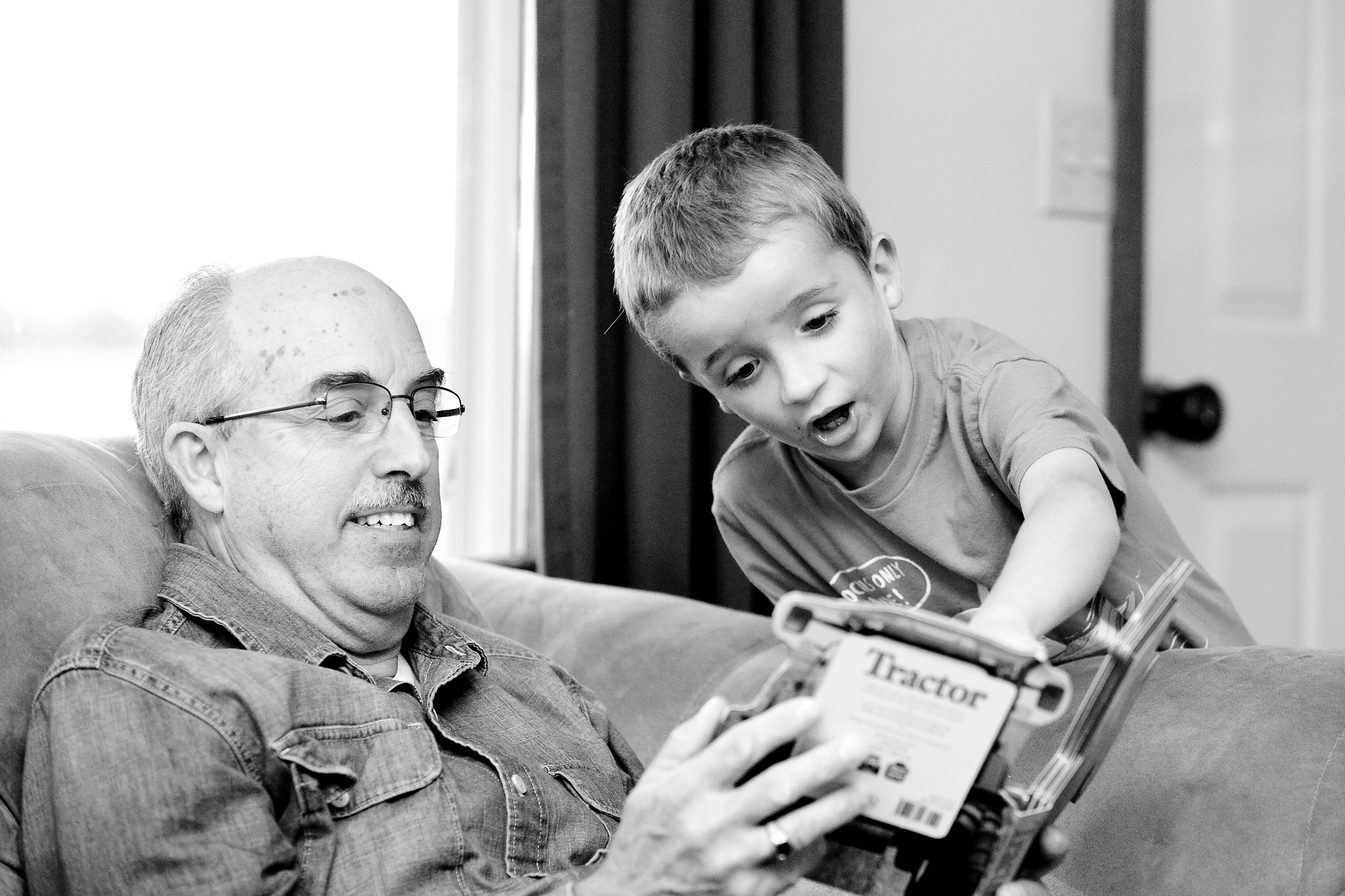 Man reading book and boy pointing at pictures