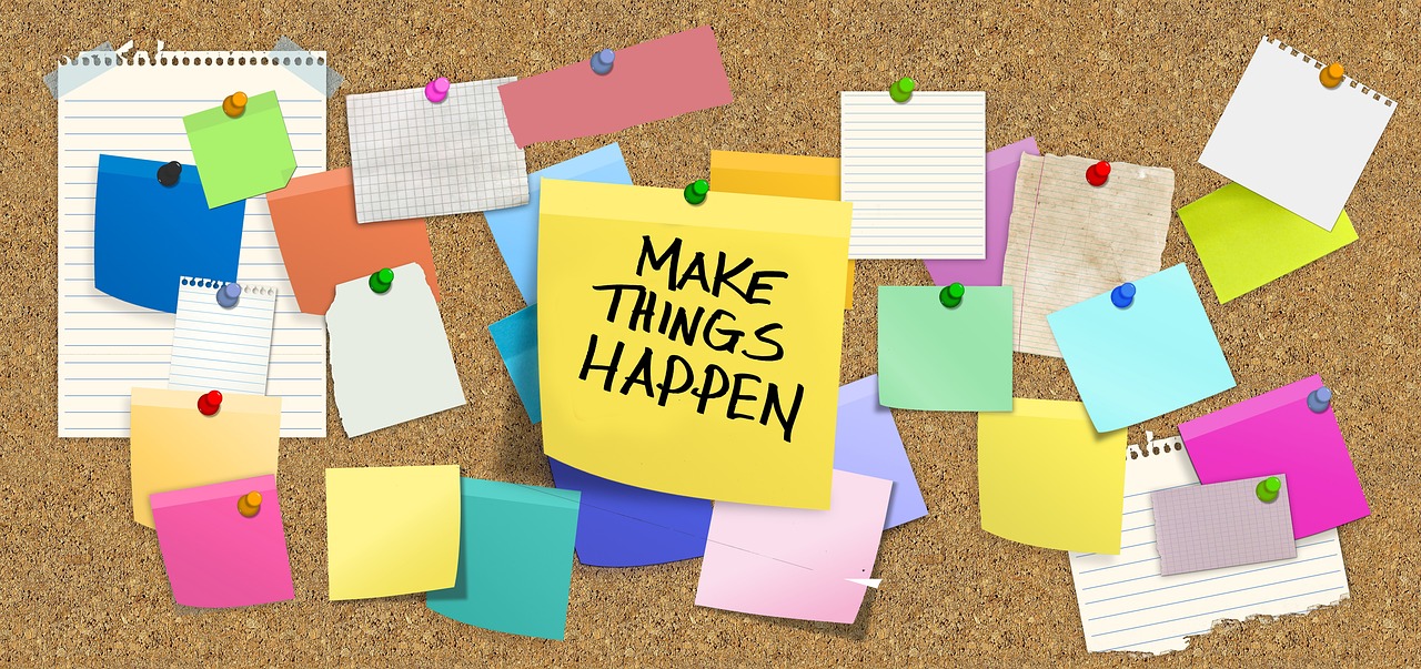 Bulletin board with posts its. Middle post it says, "Make Things Happen".