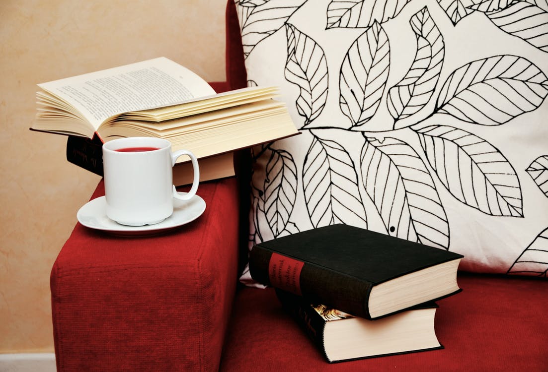 Books sitting on a chair with a cup of tea