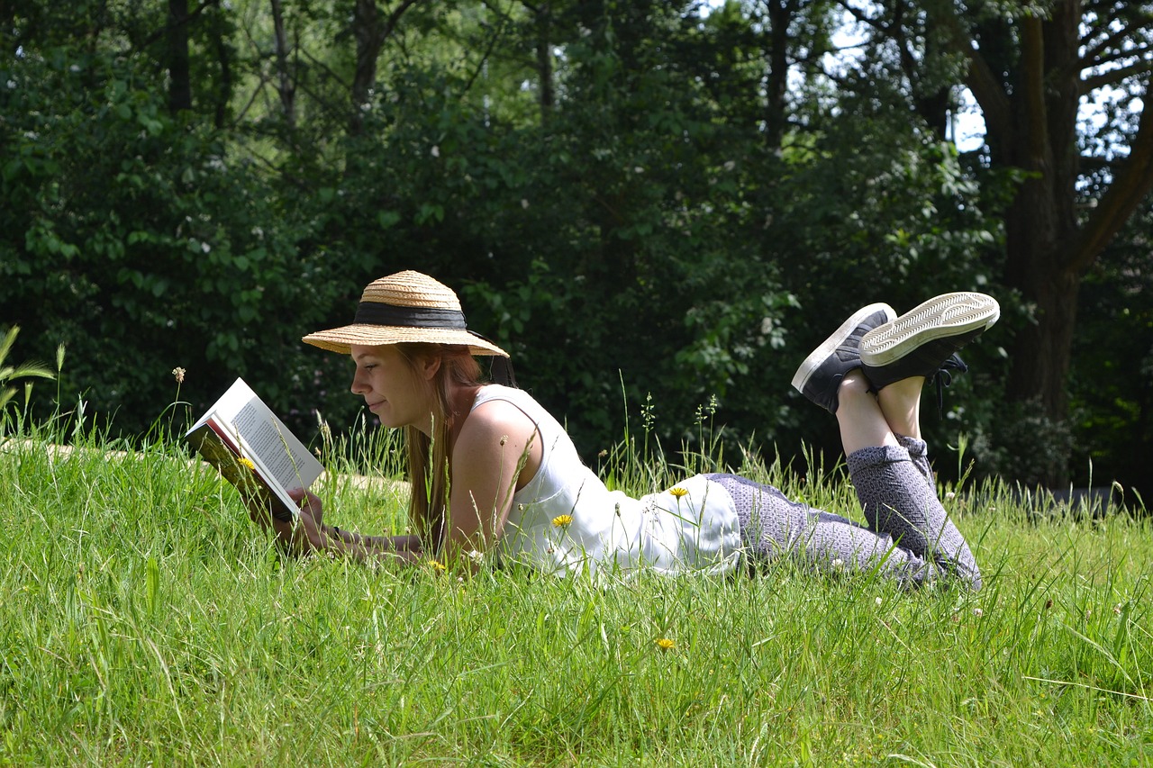 Woman laying in grass reading a book