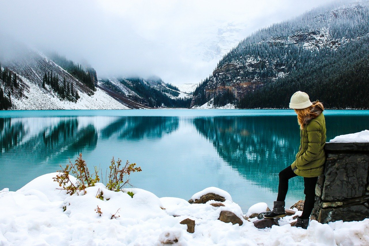 Woman standing by lake with mountain in the background